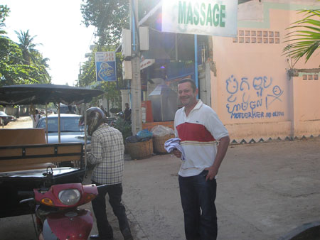 Why is Simon stood under sign for Massage shop?